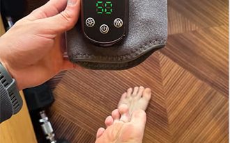 The Foot Companion held in one hand, showing its compact size and controls